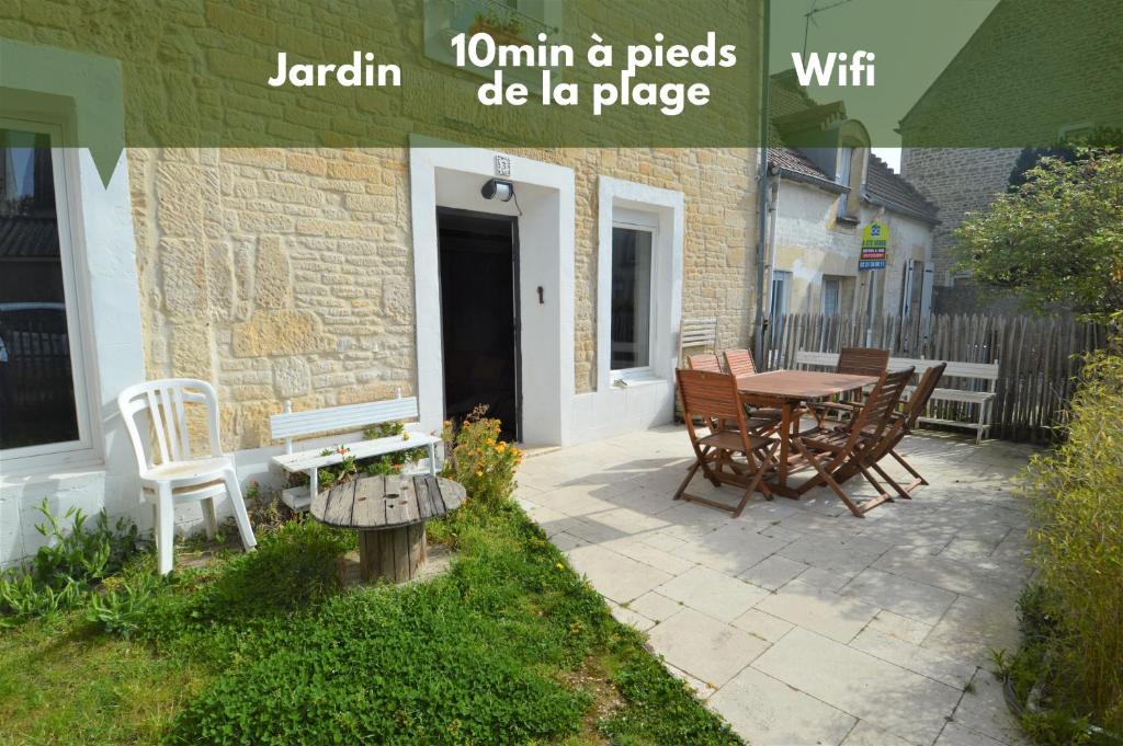 滨海吕克Maison de charme bord de mer - Avec jardin et wifi的一个带桌椅的庭院和一座建筑