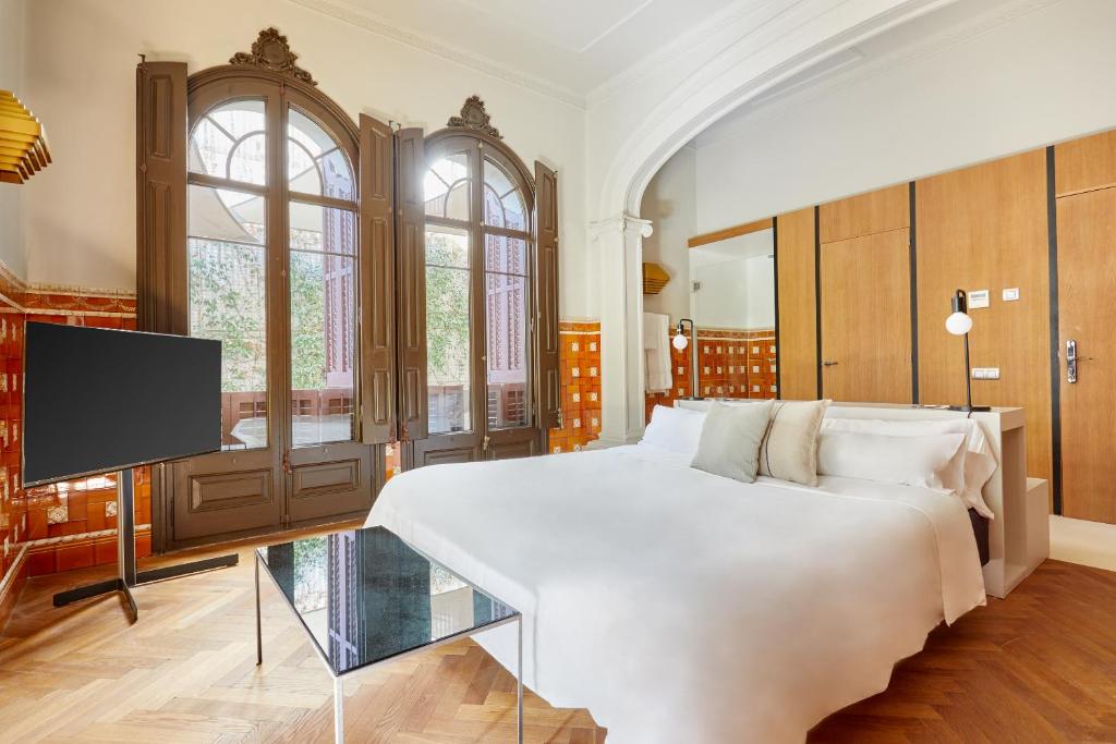 巴塞罗那Le Palacete powered by Sonder的卧室配有一张白色大床和一台平面电视。