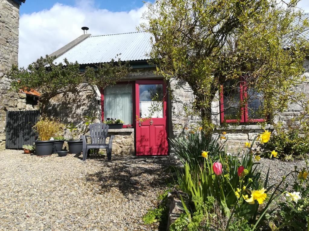 GlendreeDruid cottage的石头小屋,设有红色的门和鲜花