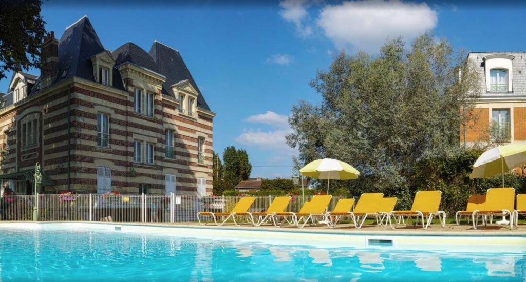 卡布尔Cosy appartement dans une villa avec piscine, proche du centre et de la mer的一座带椅子和遮阳伞的游泳池位于一座建筑旁边
