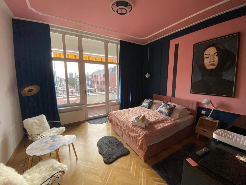 什切青Apartamenty Royal Point Bed & Bath的卧室配有一张床,墙上挂有绘画作品