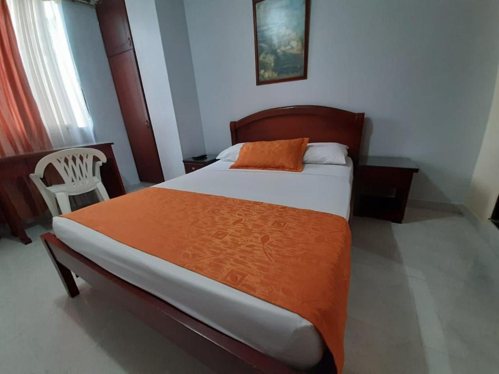 伊瓦格Hotel Center的一间卧室配有一张带橙色毯子的大床