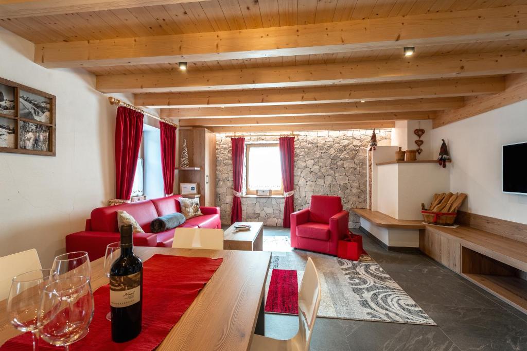 维哥迪法萨Ciasa Sas da le Doudesc的客厅配有红色家具和一瓶葡萄酒
