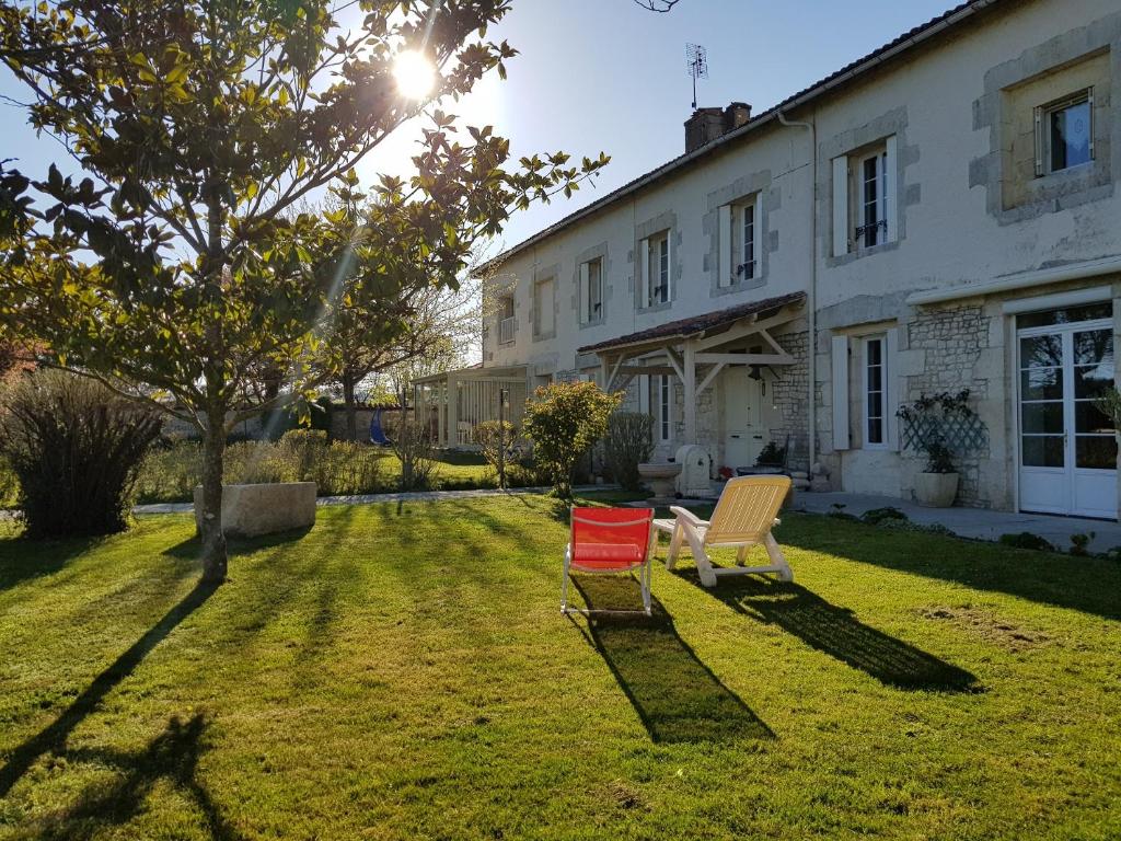 圣哲伦Domaine de Pelouaille - chambre d'hôtes的两把椅子坐在房子前面的草上