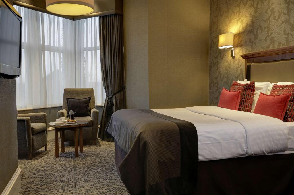 马瑟韦尔Best Western Motherwell Centre Moorings Hotel的配有一张床和一把椅子的酒店客房