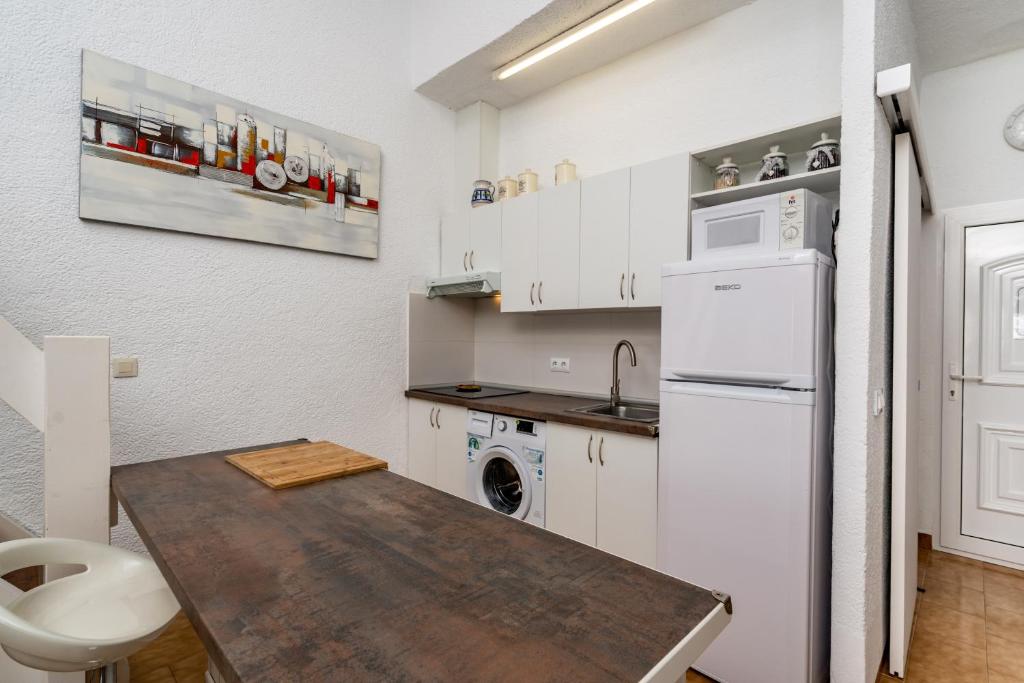 德尼亚Solymar的厨房配有木桌和白色冰箱。