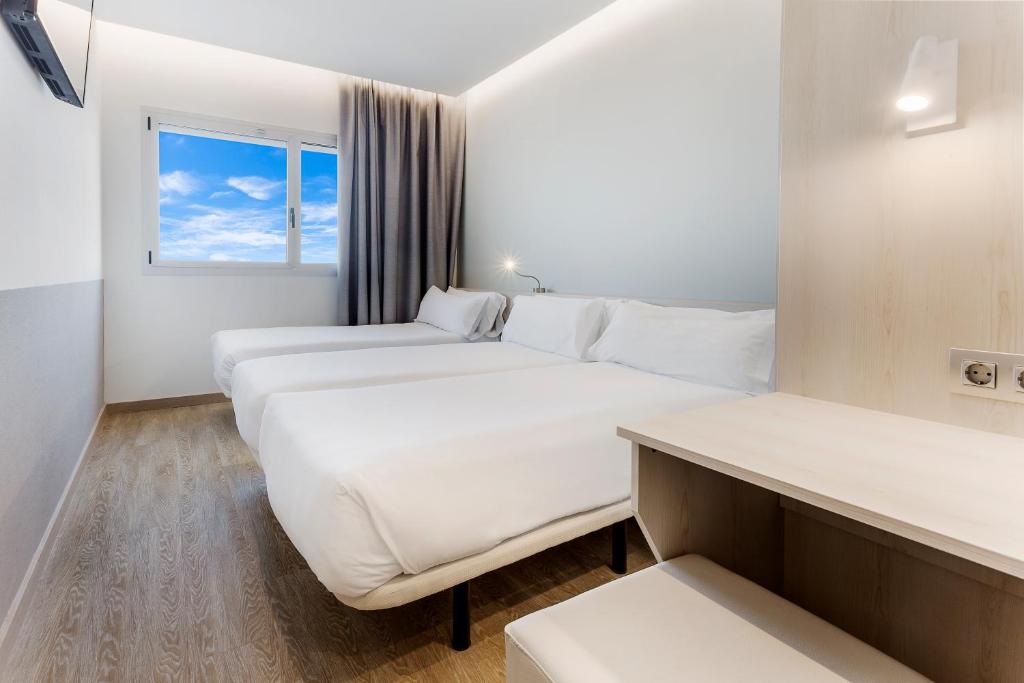 维拉德塞斯B&B HOTEL Barcelona Viladecans的酒店客房设有两张床和窗户。