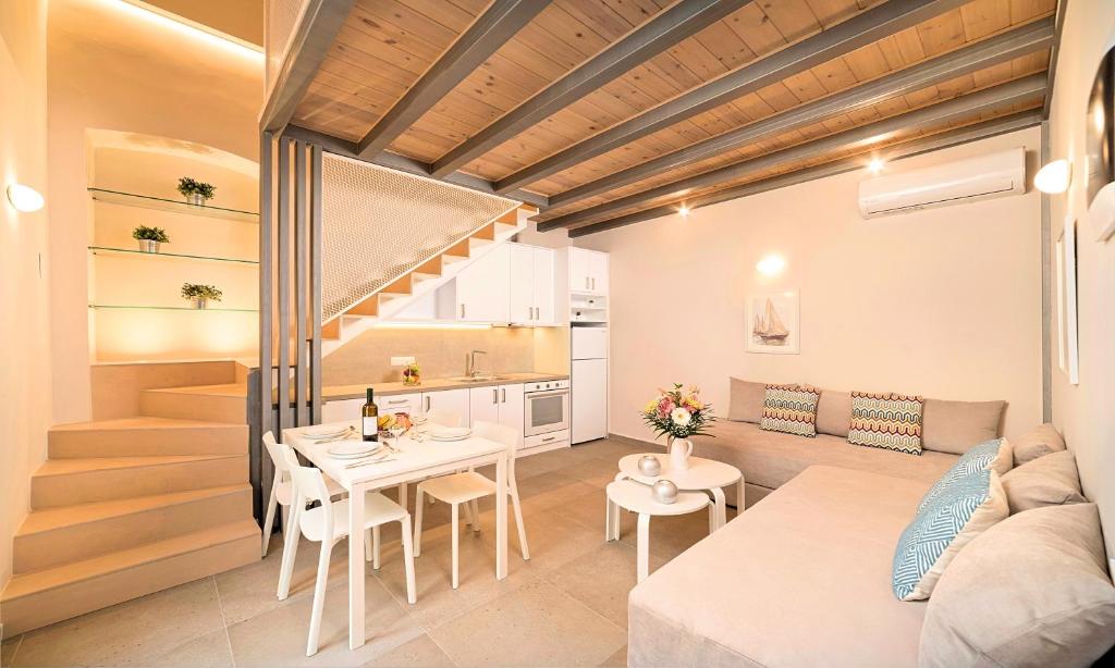 罗希姆诺Pal Calma Suites的厨房以及带桌子和沙发的客厅。