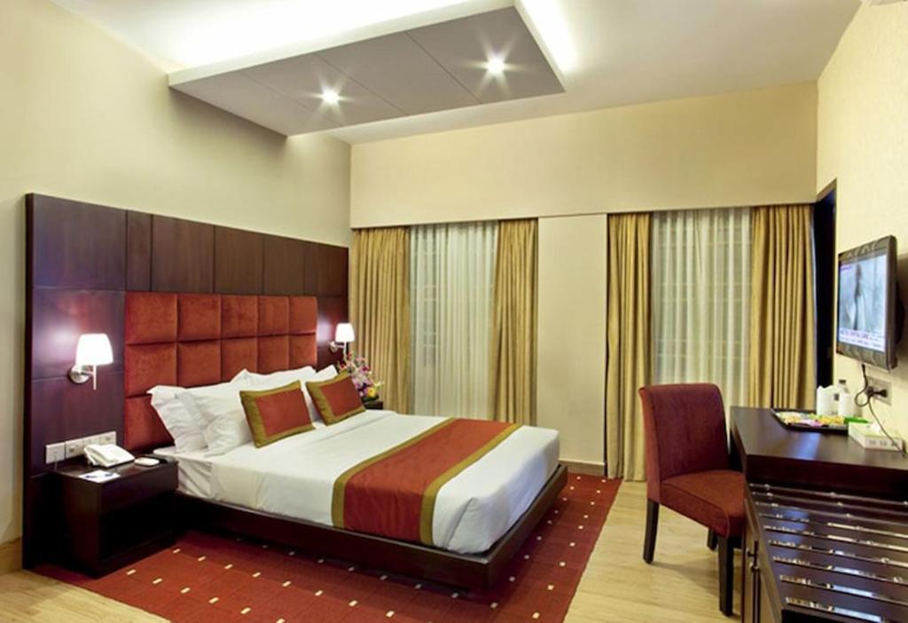 达卡West Park Inn的酒店客房设有一张大床、一张书桌和一张书桌。