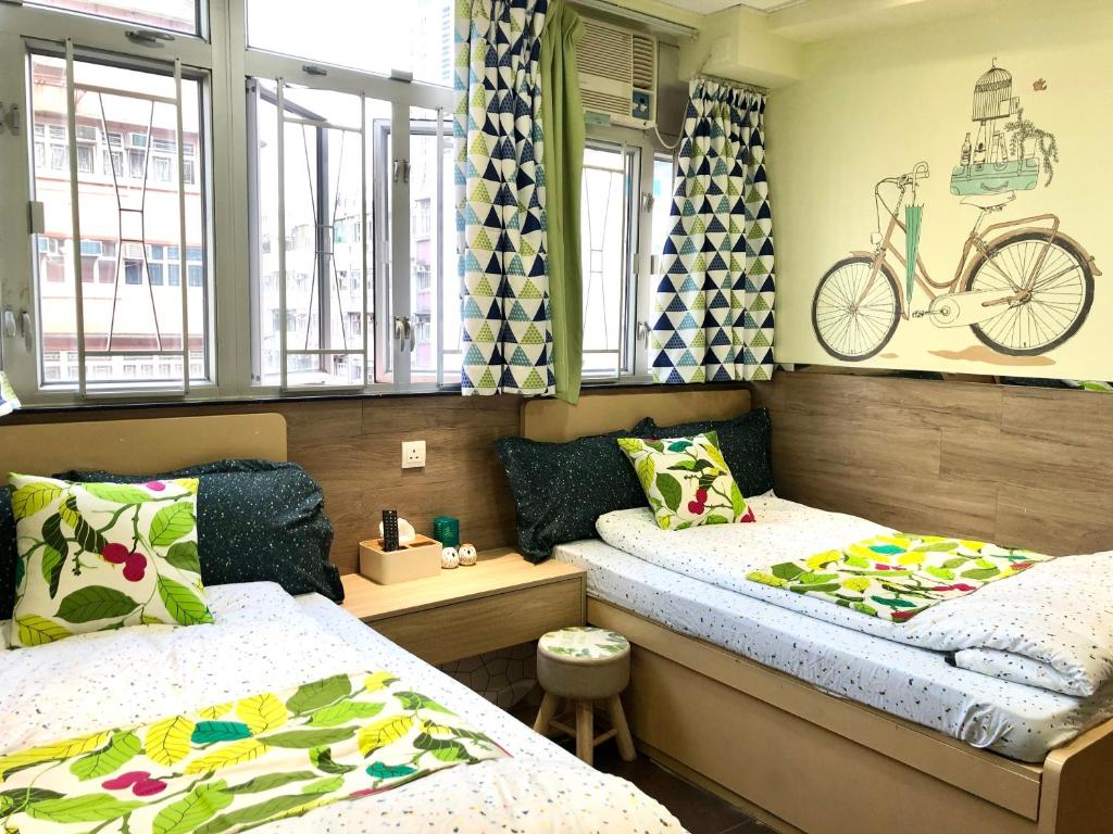 香港Paris Guesthouse-Tsim Sha Tsui Mansion的一间设有两张床的房间和墙上的自行车
