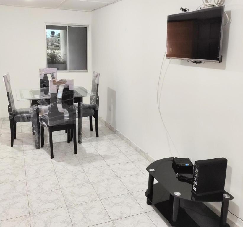 里奥阿查Apartamentos Riohacha的一间带桌椅和电视的用餐室