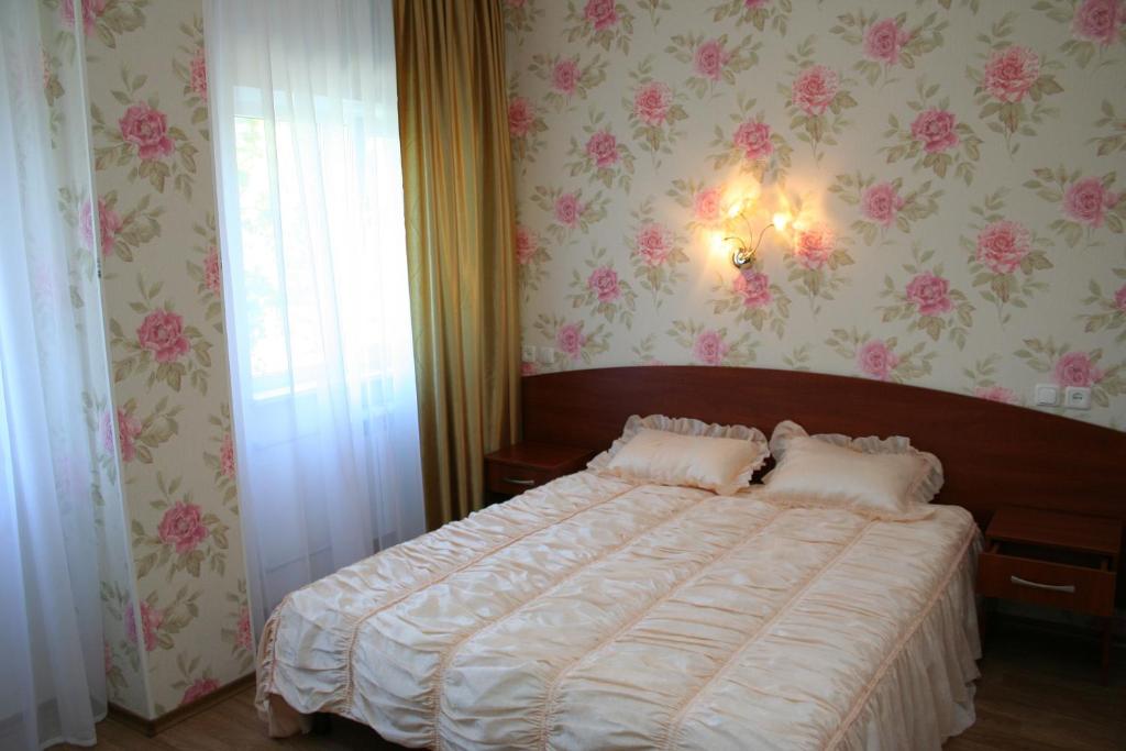 哈尔科夫亚历山大酒店的一间卧室配有一张粉红色花卉壁纸的床