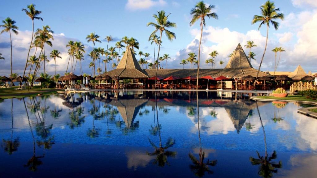 瓜拉久巴Vila Galé Resort Marés - All Inclusive的棕榈树和建筑度假村的游泳池