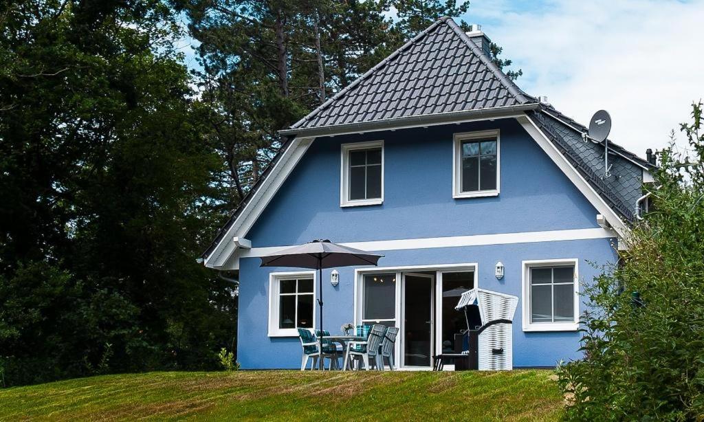 阿伦斯霍普Strandhaus Gabriella 02的蓝色的房子,配有椅子和雨伞