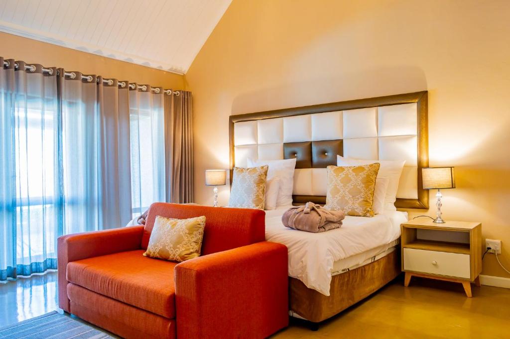 BalgowanMount Shekinah Country Hotel的一间卧室配有一张大床和一张红色椅子