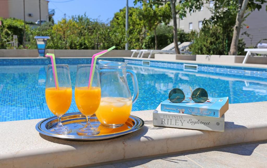斯普利特Villa Žnjan的两杯橙汁,放在游泳池旁的托盘上