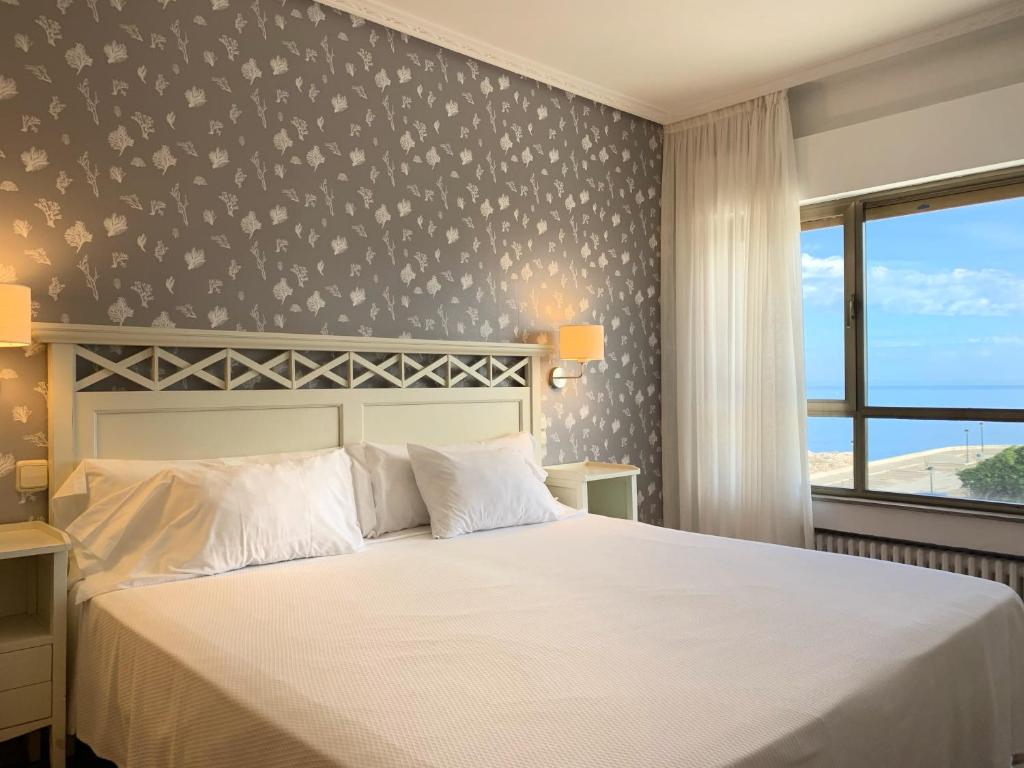 苏安塞斯Hotel Playa de Los Locos的卧室配有白色的床和窗户。