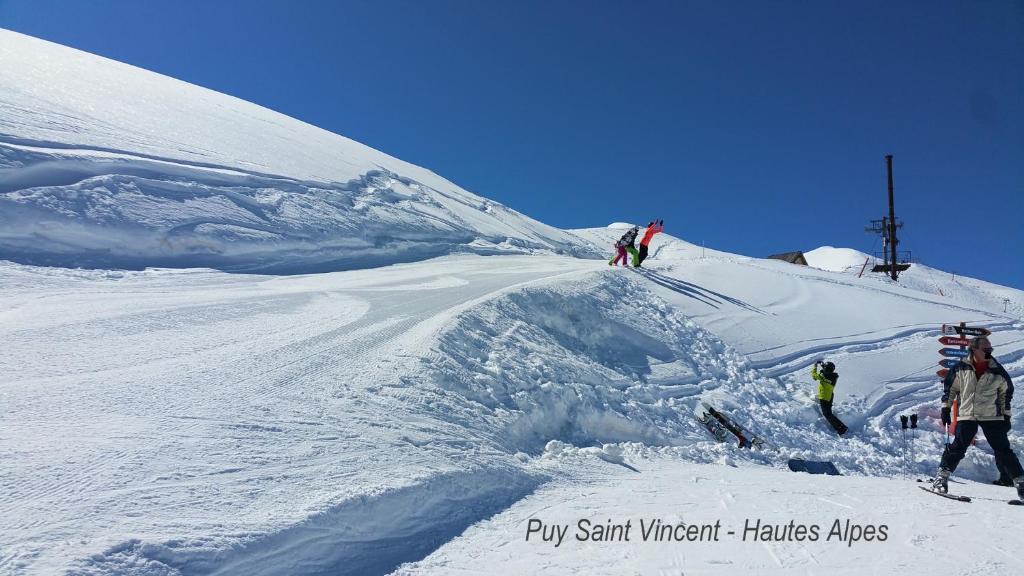 皮伊圣万桑Le Skisun - Massif et Parc national des Ecrins - Puy Saint Vincent 1800的一群人沿着雪覆盖的斜坡滑雪