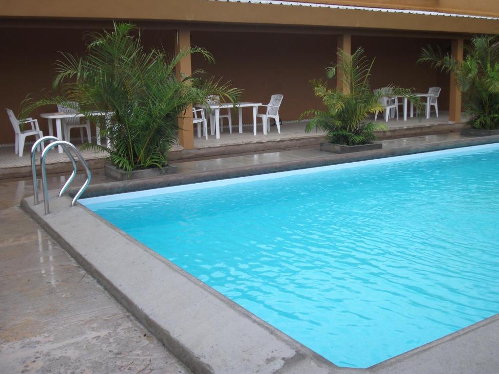 杜阿拉Residence Japoma的大楼旁的游泳池配有桌椅