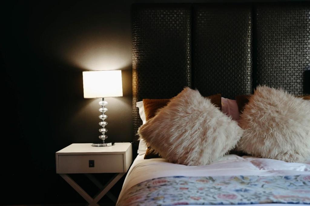库鲁曼The Hedge Guesthouse的一间卧室配有一张带台灯和枕头的床