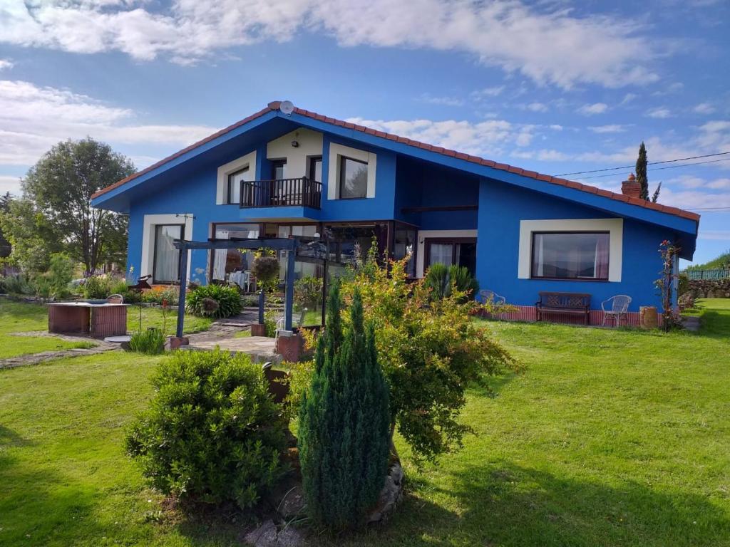QuintuelesSon de Mar Hotel rural & Apartamento的蓝色房子,带绿色庭院