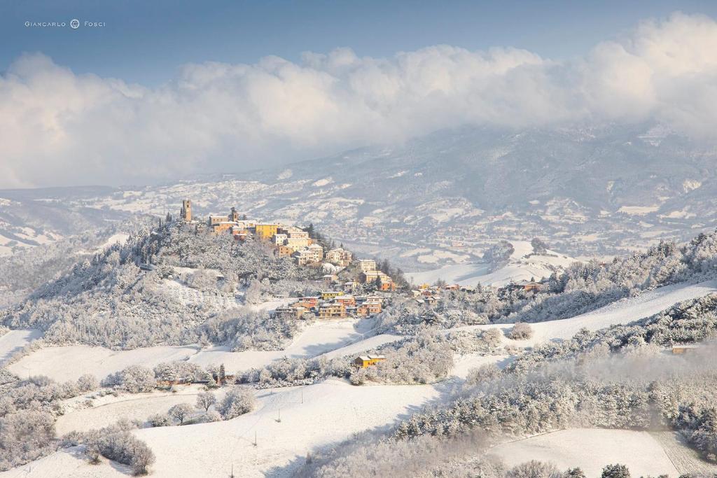 PeglioLa vedetta del Montefeltro的雪中山顶的房子