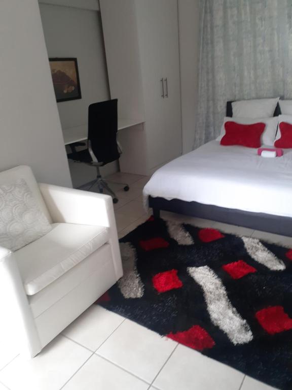肯普顿帕克Ruros Guest House的一间卧室配有一张床、一张沙发和一把椅子