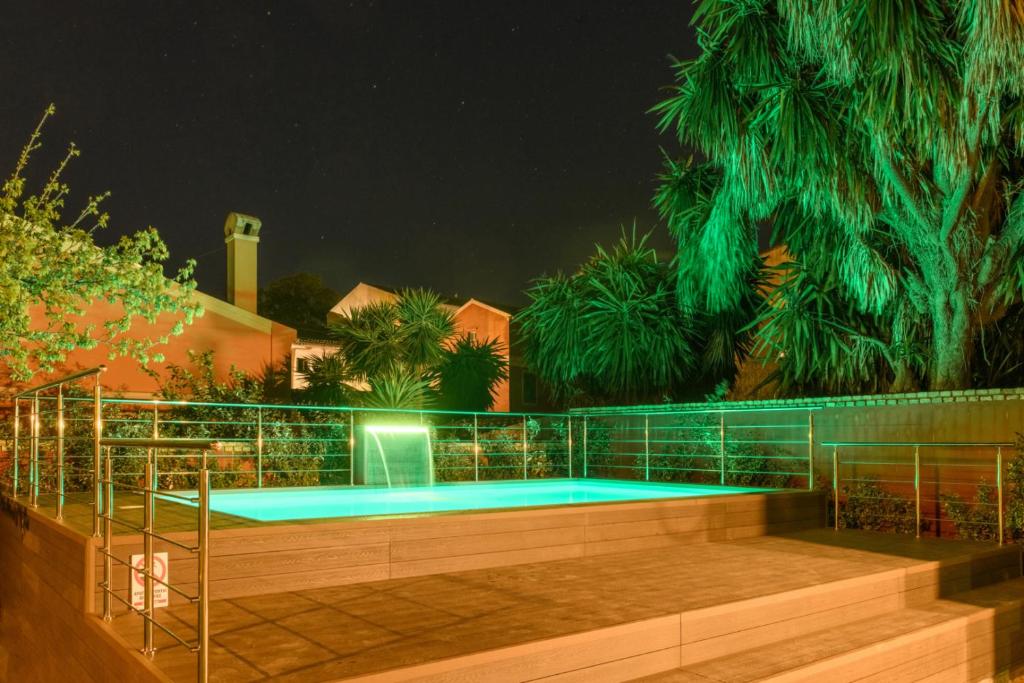 科孚镇Villa Nitsa的游泳池在晚上设有围栏和树木