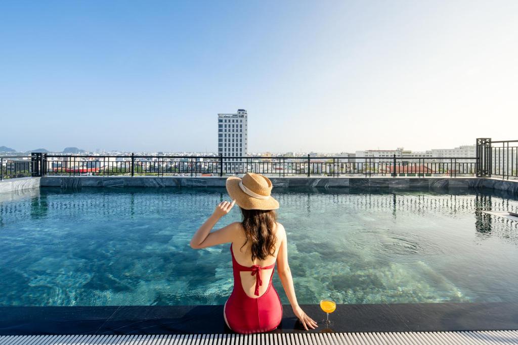 岘港Tan Phuong Nam Hotel & Apartment的坐在游泳池旁的戴帽子的女人