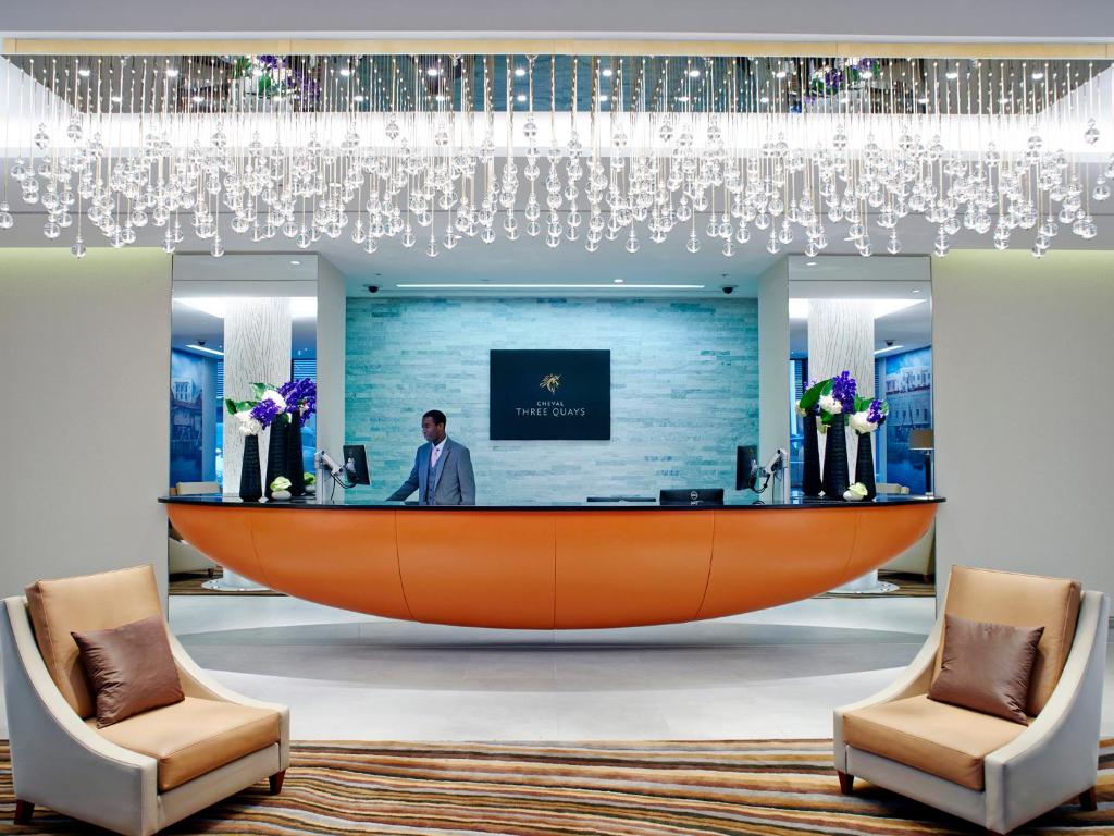 伦敦仕骅廷三码头酒店公寓的酒店大堂的接待区,设有大型橙色办公桌