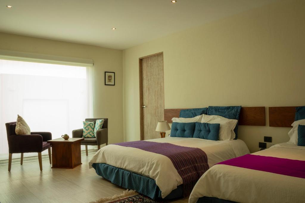 科米坦德多明格斯Hotel Nak'An Secreto Maya的酒店客房设有两张床和窗户。