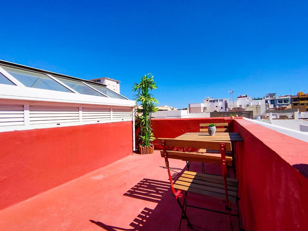 大加那利岛拉斯帕尔马斯Alma Canaria Apartments & Rooms的阳台上红色墙壁上的木凳