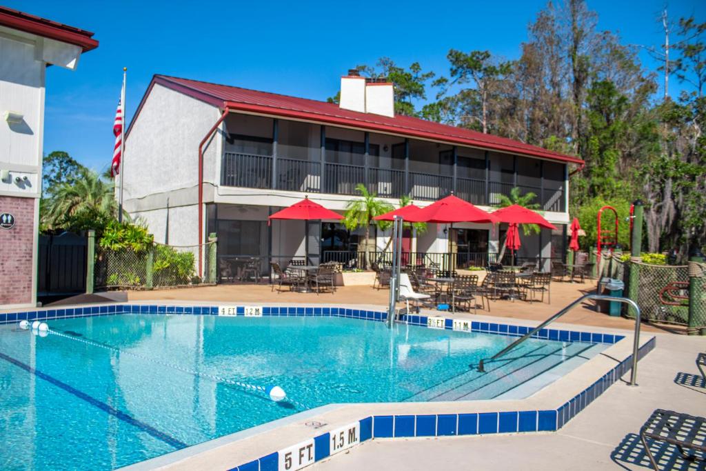 奥兰多钻石度假村布莱恩的西班牙湾公寓式酒店的酒店前的游泳池配有红伞