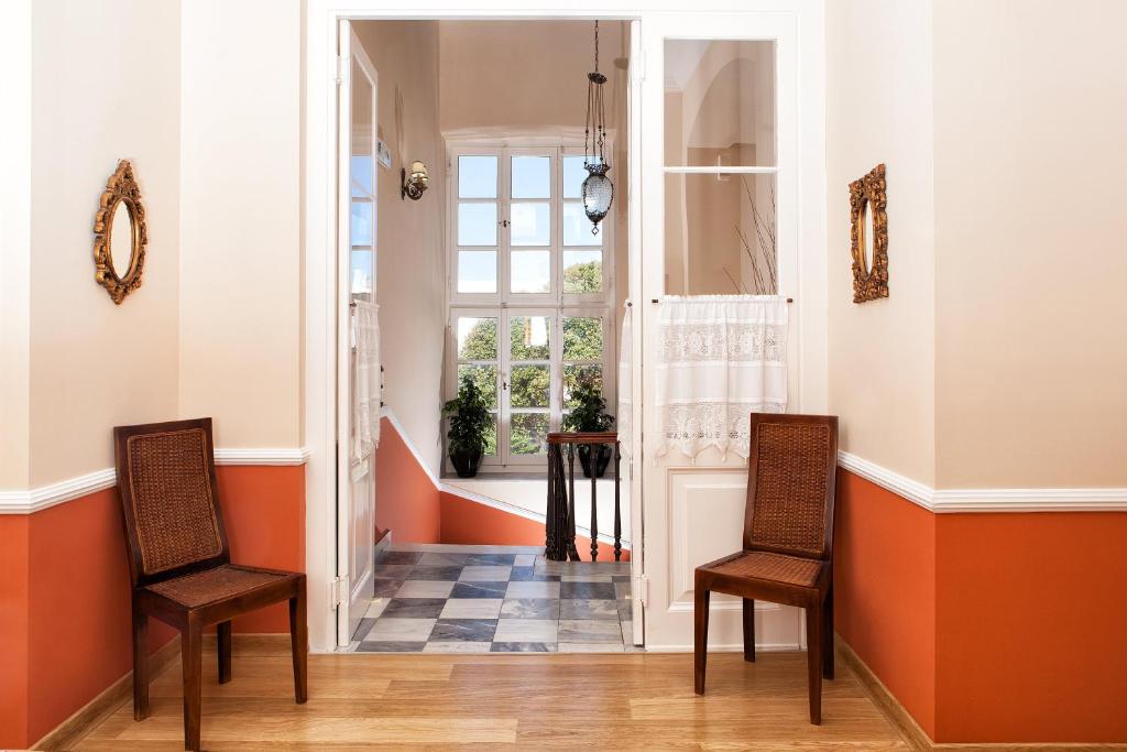 安德罗斯Egli Hotel的走廊设有两把椅子,墙壁橙色和白色