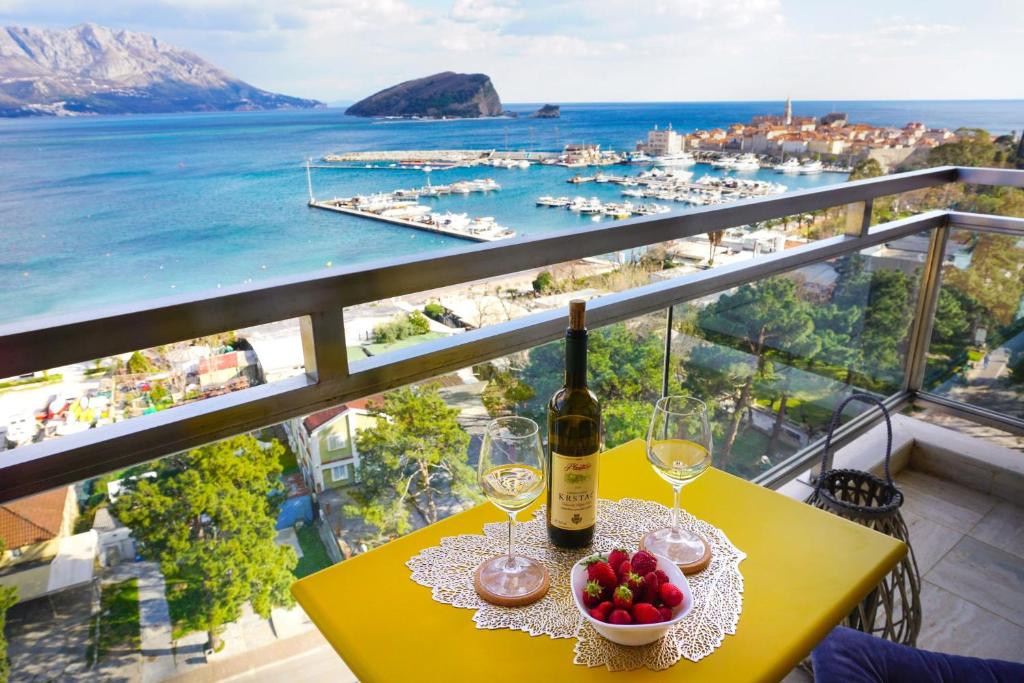 布德瓦Four Views Apartments的一张桌子,上面放着一瓶葡萄酒和一碗水果