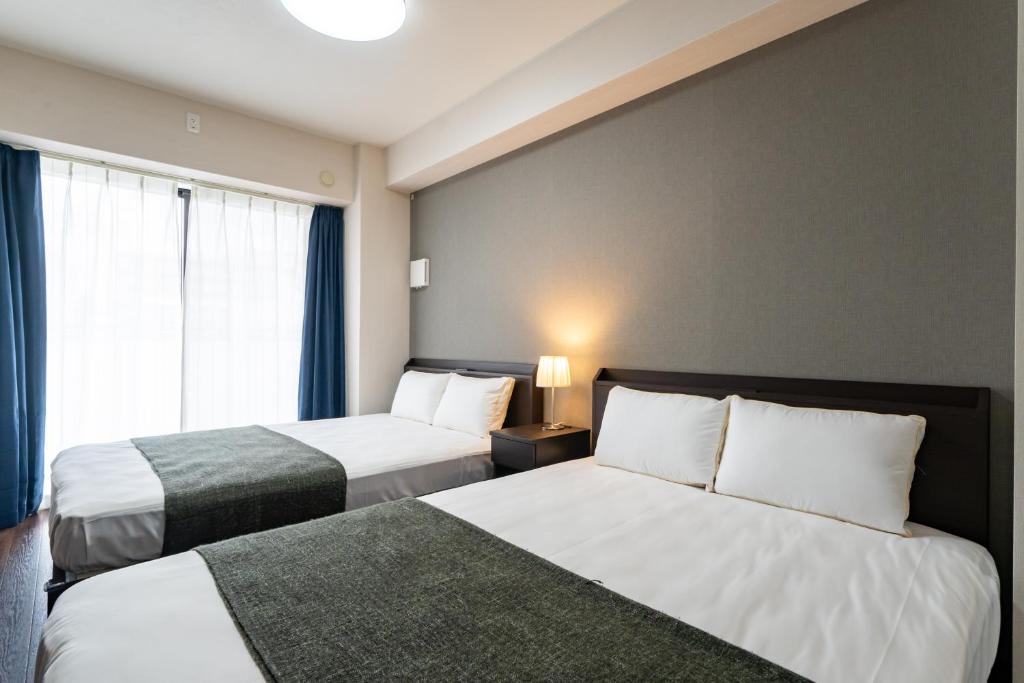 大阪Hotel Piacere NAMBA的酒店客房设有两张床和窗户。