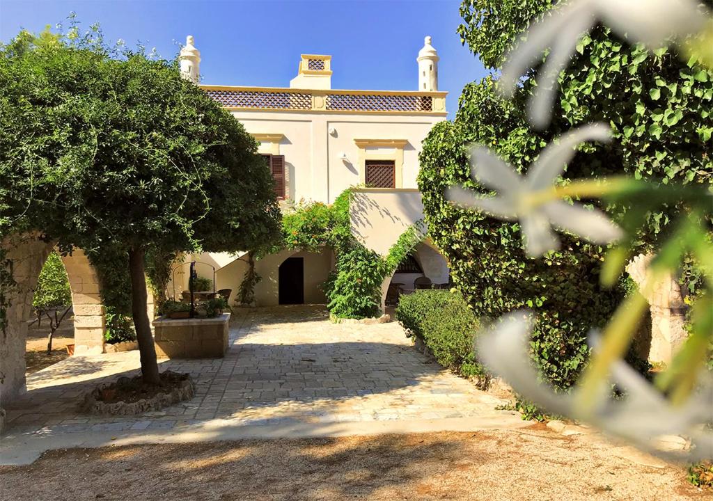 普尔萨诺Antica Casina B&B di Charme的前面有树木的白色房子