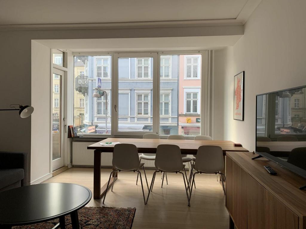 哥本哈根ApartmentInCopenhagen Apartment 1423的客厅配有桌椅和大窗户