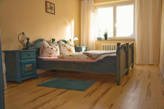 GräfenrodaFerienwohnung Wolf的一间卧室设有一张床和一个窗户,铺有木地板
