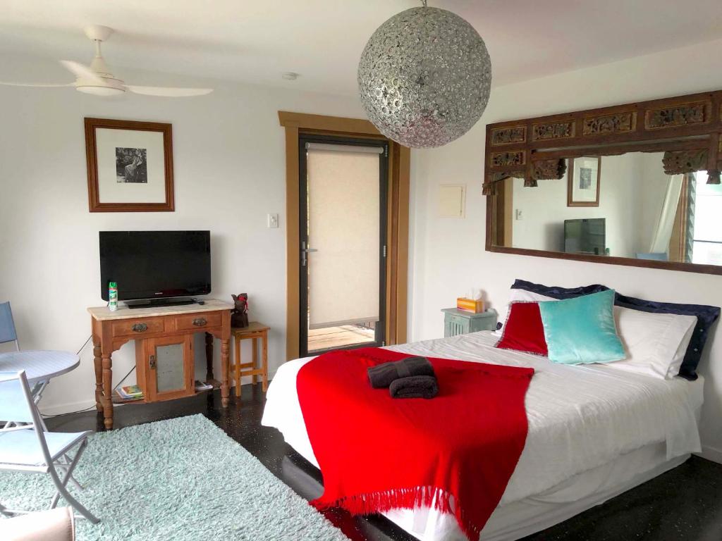 UkiTHE GOLDEN RETREAT POOL HOUSE的一间卧室配有一张带红毯的床和一台电视