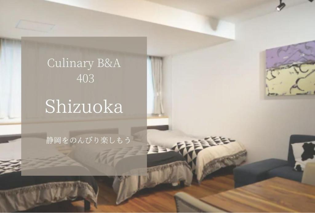 滨松Culinary Bed&Art2 403的客厅配有两张床和一张桌子