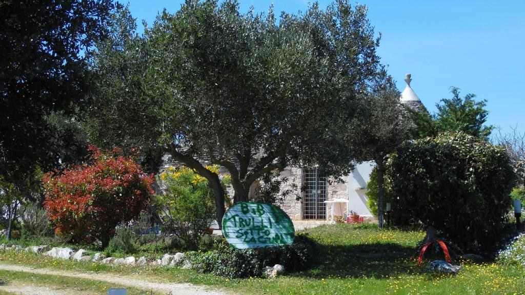 马丁纳弗兰卡B&B Trulli sotto La Cupa的草上有一棵树和一个标志的房子