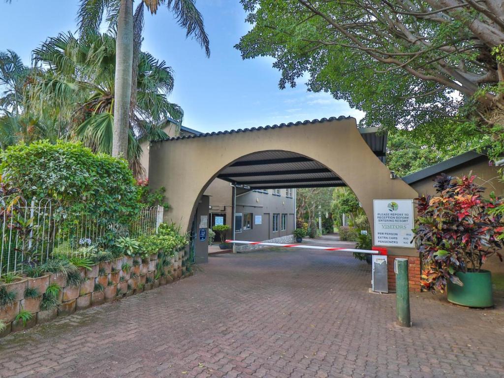 IllovoVilla Spa Holiday Resort的拱门,通往树木和植物的建筑