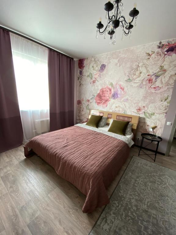 苏尔古特Уютная квартира на Ауре的一间卧室配有一张带花卉壁纸的大床
