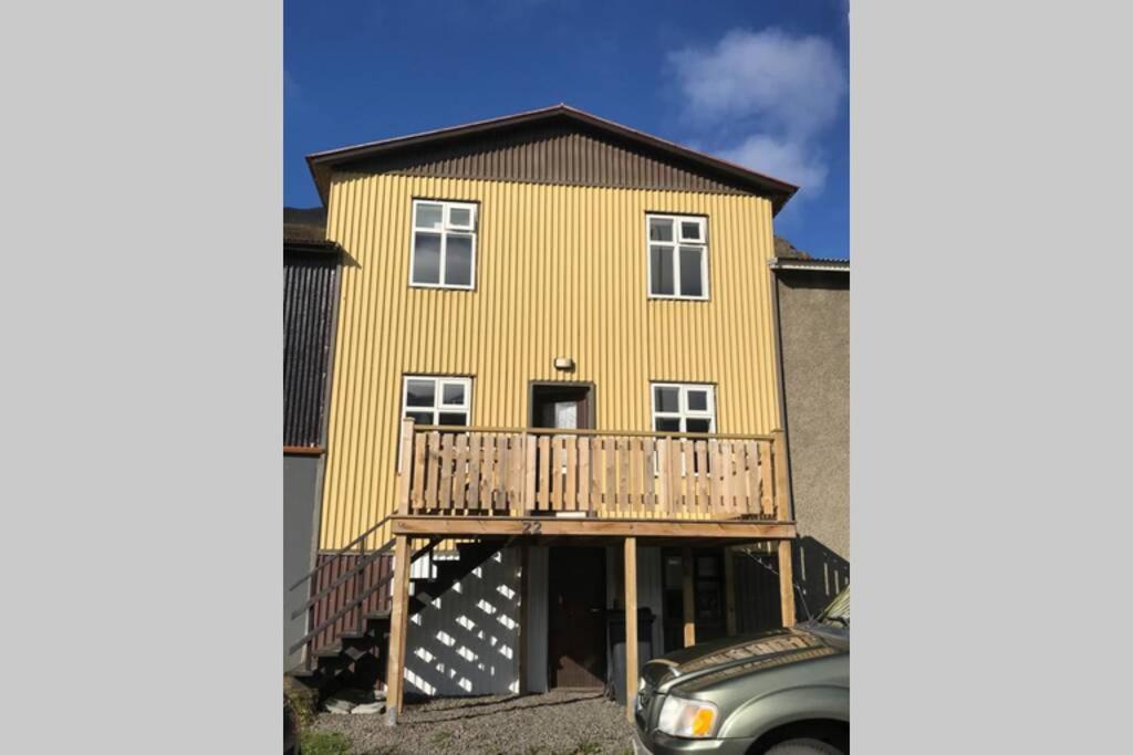 锡格吕菲厄泽House with a warm soul in North Iceland的带阳台和汽车的大型黄色房屋