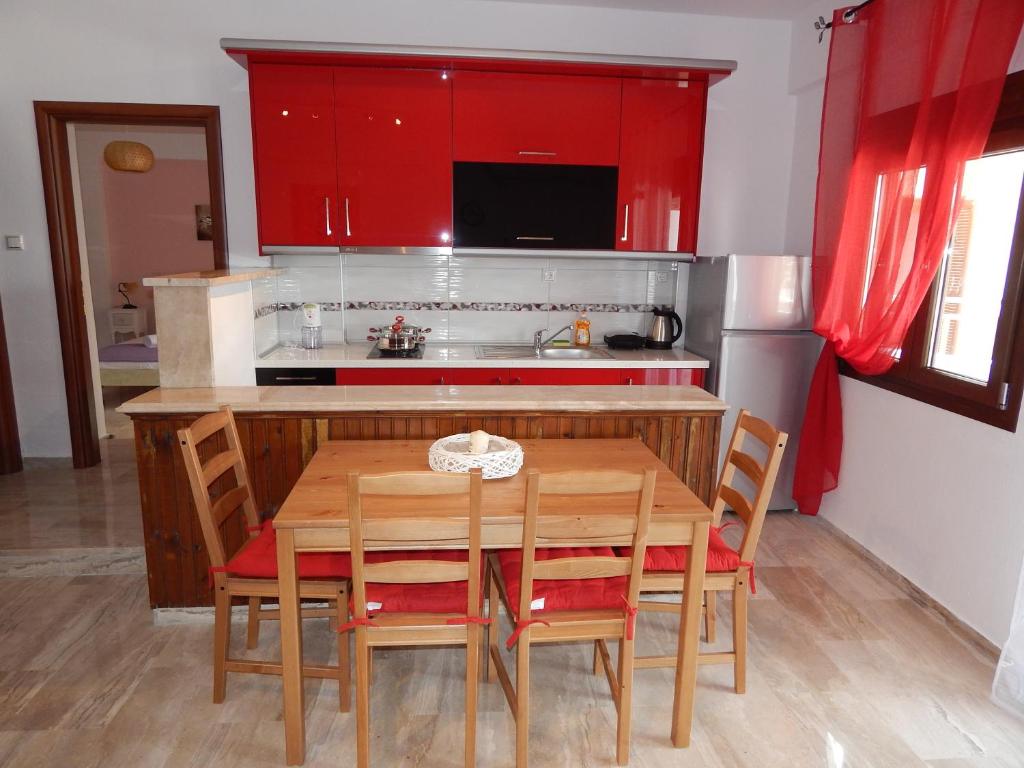 尼基季Palm House Nikiti - Apartments Vicky的厨房配有木桌和红色橱柜。
