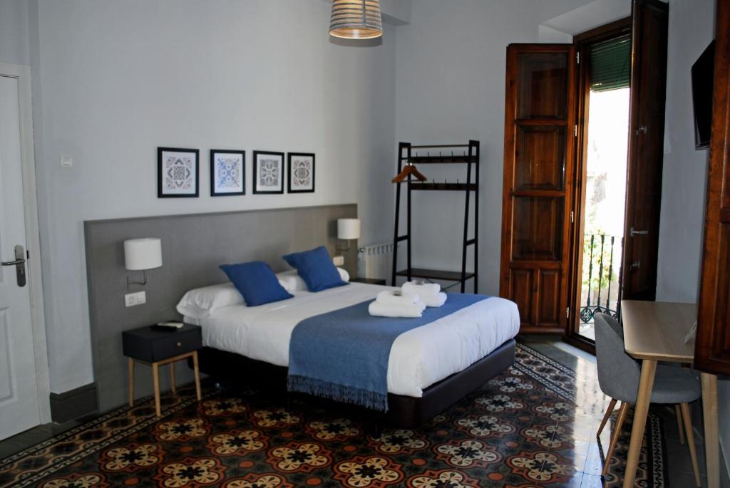格拉纳达La Perla Granada Suites的一间卧室配有一张带蓝色枕头的大床