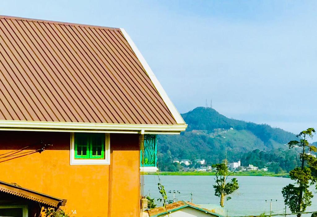 努沃勒埃利耶Serendipity Lake Artistic Bungalow by Heidis Home的一座享有水体景致的橙色建筑