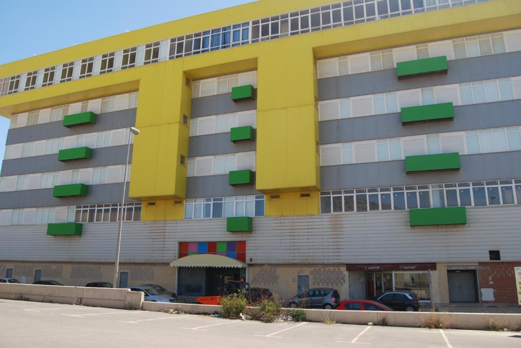 卡塔赫纳地中海之旅公寓酒店的一座黄色和灰色的建筑,停车场内有车辆停放