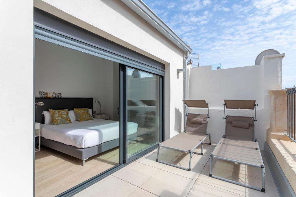 阿利坎特Arenal Suites Alicante的一间带一张床和两把椅子的卧室,位于阳台